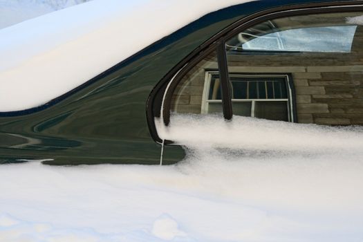 Car stuck in the deep snow after the snowstorm reflects the buildings around.