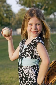 Cute young girl in summer dress with a baseball