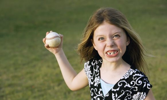 Cute young girl in summer dress with a baseball