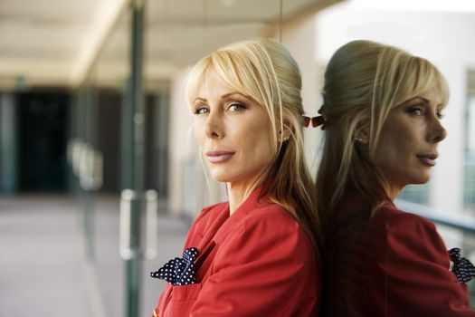 Blonde Businesswoman leaning against a reflective surface