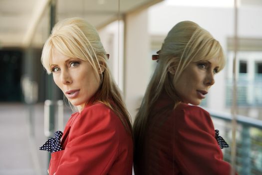 Blonde Businesswoman leaning against a reflective surface