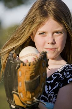Cute young girl in summer dress with a baseball