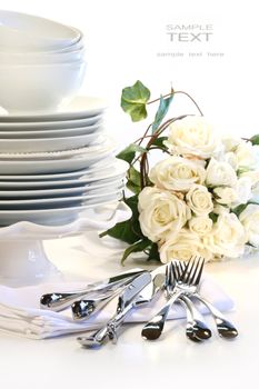 White plates stacked with utensils and roses for wedding