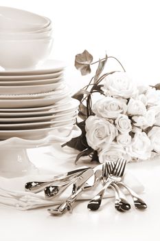 White plates stacked with utensils and roses for wedding/ BW