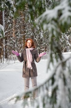 Happy red-haired woman having fun on winters day in forest.