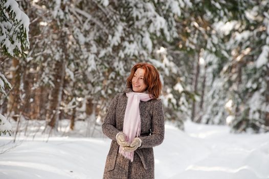 Happy red-haired woman having fun on winters day in forest.