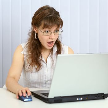 Angry woman browses websites with a laptop