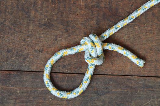 Rope with knot and loop lying on wooden background
