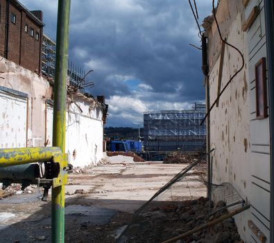 A photograph documenting the demolition of a building, under a brooding sky