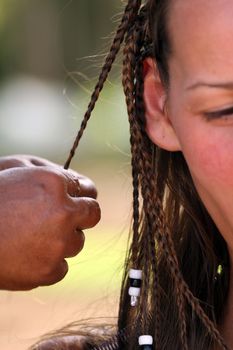 African woman making european woman braids