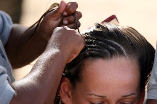 two caribbean women making braids on the head