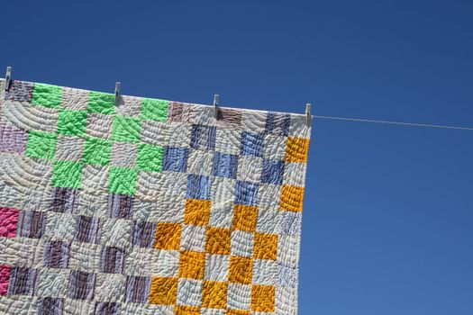 Laundry. Bright patchwork counterpane hanging to dry on a clothes-line.