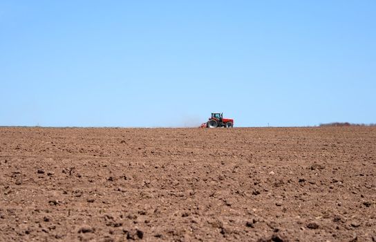 Farmer working on him tractor in the spring field, plowing land.