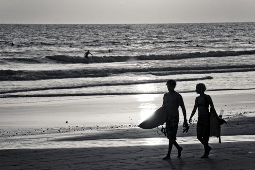 Two surfers walk home after a long day in the surf.