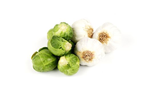 White raw garlic bulbs with green raw sprouts on a reflective white background