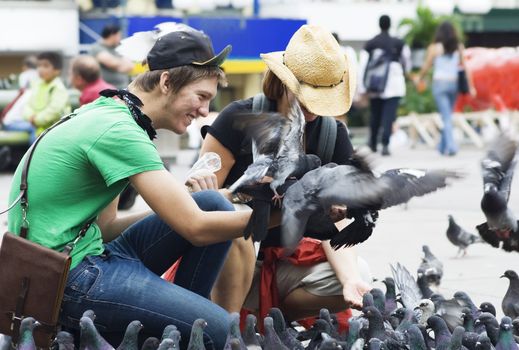 Tourists feeding pigeons in a plaza in San Jose, Costa Rica