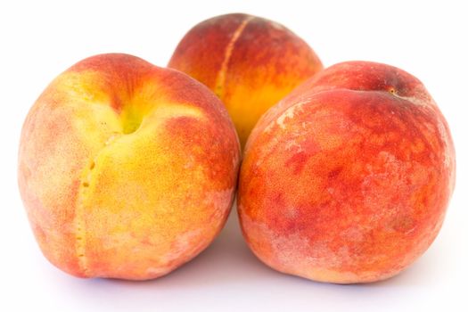 Three ripe peaches on a white background.