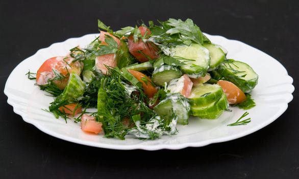 salad on a white plate on a black background