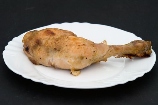 The fried part of a chicken on a white plate on a black background