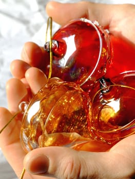 Red and golden Christmas glass ornaments in man's hands