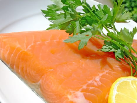 Close-up of a raw salmon fillet with lemon and parsley