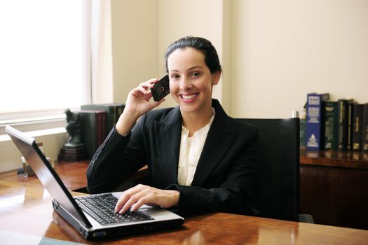 female lawyer at office talking on phone and using laptop