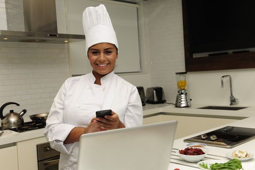 Happy chef cooking in kitchen and typing sms