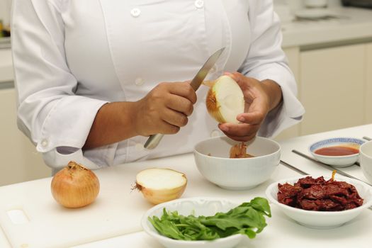 Happy chef cutting onions in a modern kitchen