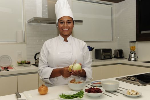 Happy chef cutting onions in a modern kitchen