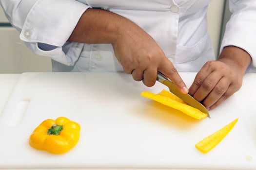 Professional chef cutting yellow pepper