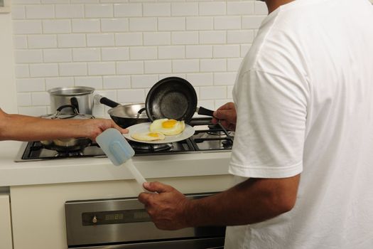 Employee preparing a fried eggs and putting them on a plate