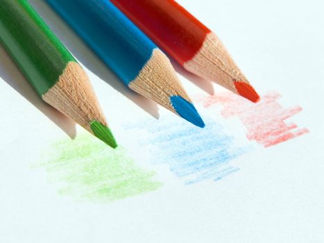 Three colored pencils on white paper sheet