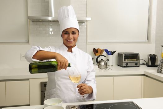 Happy chef cooking using white wine in kitchen