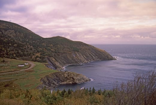 Meat Cove, Nova Scotia is the Northern-most settlement of Cape Breton Island. A solitary house sits on the rugged mountain coast at sunset.