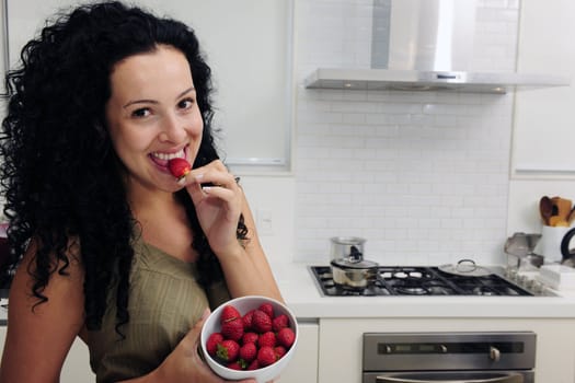 Woman eating strawberries in a modern kitchen