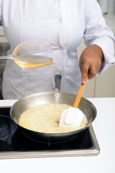 Chef cooking risotto pouring white wine into the pan