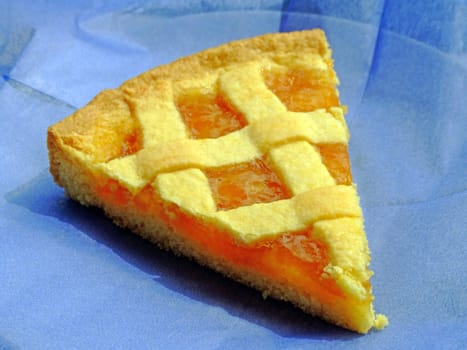 Slice of apricot marmalade tart on a blue paper napkin