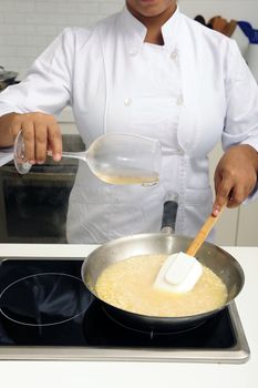 Chef cooking risotto pouring white wine into the pan