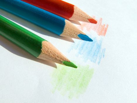 Three colored pencils on white paper sheet