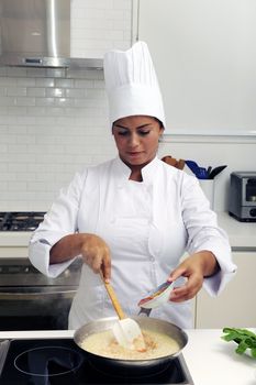 Chef cooking risotto adding sauce and stirring