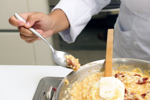 Chef cooking risotto with dried tomato stirring