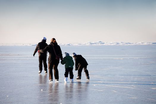 Family ice skating in natural rink frozen sea