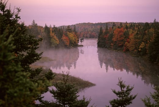 Morning mist rises from a river in Nova Scotia, Canada, on a beautiful autumn sunrise. 