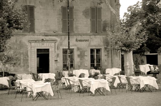 A quaint restaurant exterior with tables set and waiting for diners in the South of France. Sepia Toned.