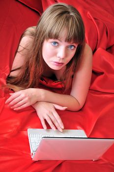 young girl using laptop at home, when she is laying in the bed