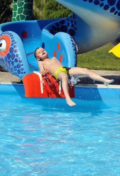 Cute and funny  little boy sliding down a water slide