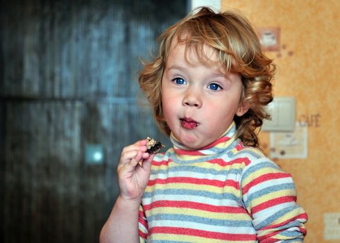 happy little girl eats sweets at the home