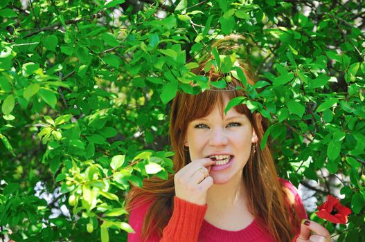 redhaired beautiful girl eats green plum