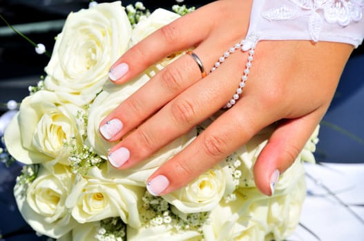 bride's hand with her new ring over white roses