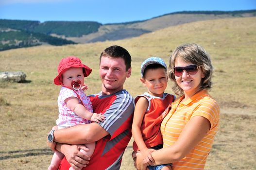 mother, father, son and daughter are outdoors, they are happy